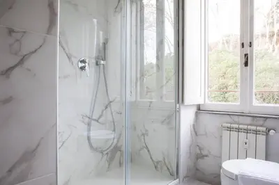 a white bathroom with a shower and a toilet at Silver Luxury Jacuzzi Suite Trastevere in Rome