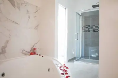 a white bathroom with a tub and a shower at Pink Intimate Jacuzzi Suite Trastevere in Rome