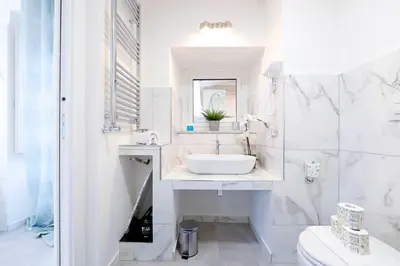 a white bathroom with a sink and a toilet at White Panoramic Jacuzzi Suite Trastevere in Rome