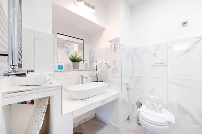 a white bathroom with a sink and a toilet at White Panoramic Jacuzzi Suite Trastevere in Rome