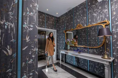 a woman standing in a bathroom with blue walls and a mirror at The Inn at the Spanish Steps Luxury Collection - Mario De' Fiori Suite in Rome