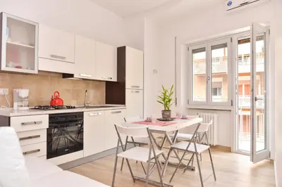 a kitchen with white cabinets and a table and chairs at Your Rhome in Rome