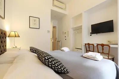 a bedroom with a white bed with a television on the wall at Residenza Mazzini in Rome