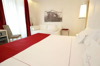 a white bedroom with a bed and a couch at Tullia&Prisca Relais in Rome