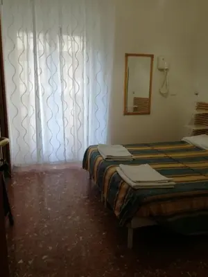 two beds in a room with a mirror and a window at Testa Gioacchino B&B in Rome