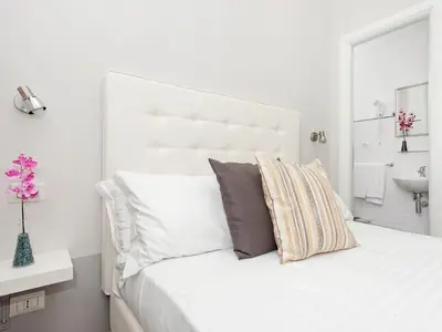 a white bedroom with a large white bed with a sink at White Rooms Colosseo in Rome
