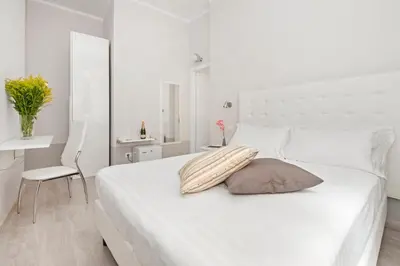 a white bedroom with a white bed and a chair at White Rooms Colosseo in Rome