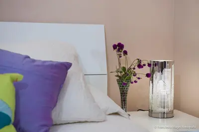 a vase with purple flowers on a table next to a bed at B&B St. Peter's Suites in Rome