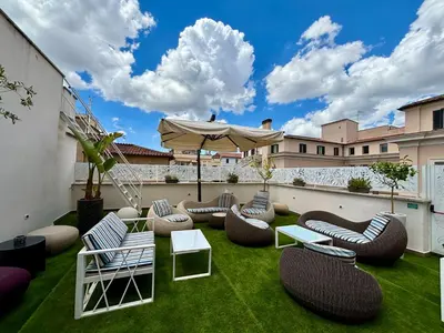 a patio with chairs and an umbrella and grass at Rome Life Hotel in Rome