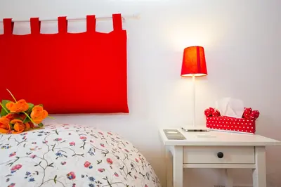 a bed with a red pillow and a table with a lamp at I Prati Di Roma in Rome