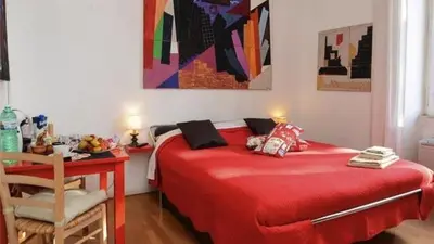 a red bed in a room with a table and a chair at B&B Villa Musa in Rome