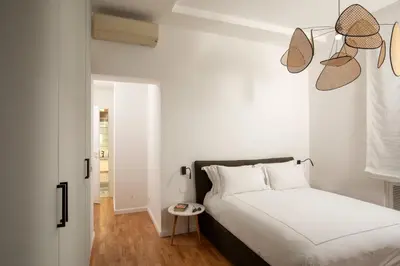 a white bedroom with a bed and a table at Casavignoni elegant 3BR home near to Spanish step in Rome