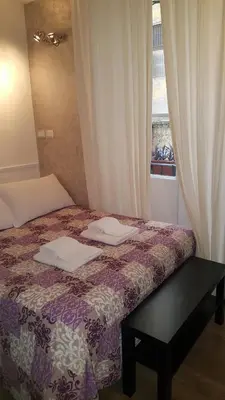a bedroom with a bed with a table and a window at Marcelina vaticans rooms in Rome