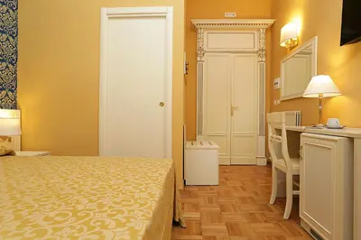 a bedroom with a bed and a table and a kitchen at DG Prestige Room in Rome