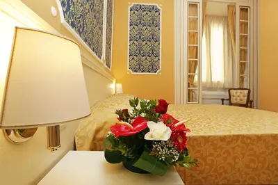 a vase of flowers on a table next to a bed at DG Prestige Room in Rome