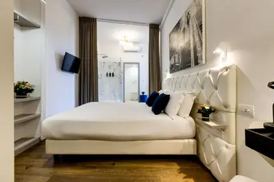 a bedroom with a large white bed with a large headboard at V Collection Piazza Farnese Luxury Suites in Rome