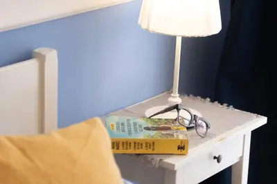 a book and glasses on a table next to a lamp at San Pietro Holidays in Rome