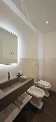 a bathroom with a toilet and a sink with a mirror at The B Place Cola in Rome