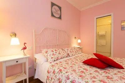a bedroom with pink walls and a bed with red pillows at Malkavacanze B&B in Rome
