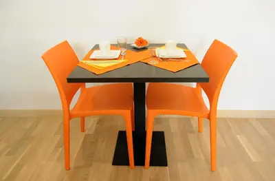 a table with orange chairs and a black table with a plate of food at Honey Rooms in Rome