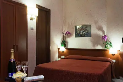 a hotel room with a bed and a table with wine glasses at Hotel Delle Muse in Rome