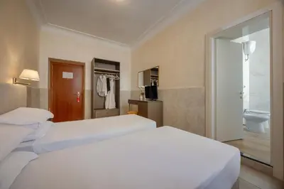 a hotel room with two beds and a window at Hotel Palladium Palace in Rome