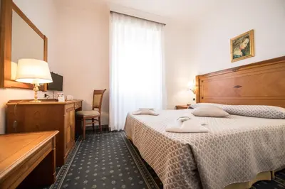 a hotel room with two beds and a table and a mirror at Quality Hotel Nova Domus in Rome