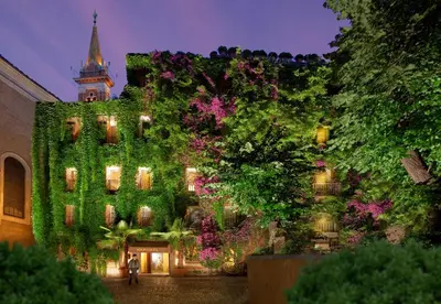 a building covered in green ivy with a clock tower at Hotel Raphaël - Relais & Châteaux in Rome