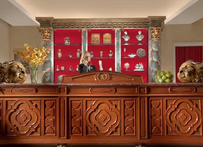 a woman standing behind a wooden dresser with a mirror at Hotel Raphaël - Relais & Châteaux in Rome