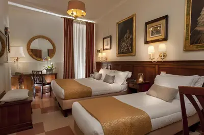 a hotel room with two beds and a mirror at Hotel Des Artistes Roma in Rome