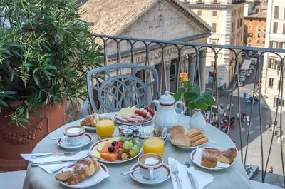 a table with breakfast food and orange juice on a balcony at Albergo del Senato in Rome