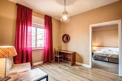 a bedroom with a bed and a desk and red curtains at City Guest House in Rome