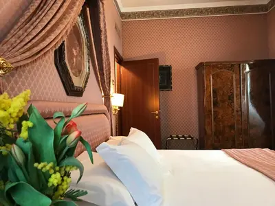 a hotel room with a bed and a vase of flowers at Hotel Mecenate Palace in Rome