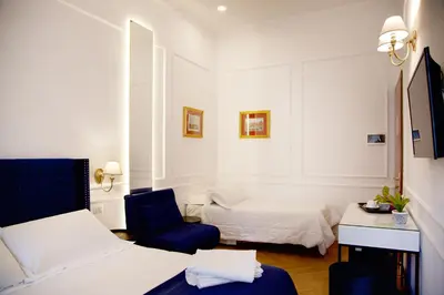 a small room with two beds and a blue chair at Hotel Silva in Rome