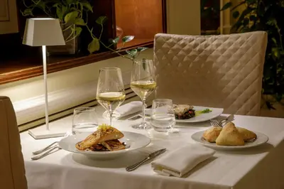 a table with two plates of food and glasses of wine at Donna Laura Palace by OMNIA hotels in Rome