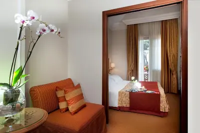 a bedroom with a mirror and a bed and a chair at Pinewood Hotel Rome in Rome