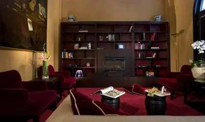 a living room with red chairs and a fireplace at Hotel dei Borgognoni in Rome