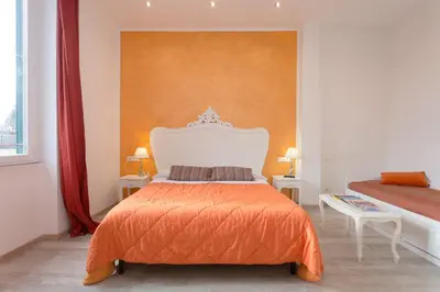 a bedroom with a large bed with an orange blanket at Colosseo Apartments and Rooms - Rome City Centre in Rome
