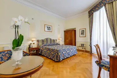 a bedroom with a bed and a table and chairs at Hotel Cellini in Rome