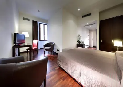 a hotel room with a bed and a desk and chair at Exe International Palace in Rome