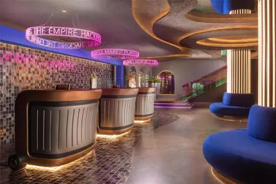 a bar with a row of stools and neon signs at nhow Roma in Rome