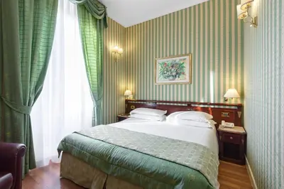 a bedroom with a large bed with green curtains at Gambrinus Hotel in Rome