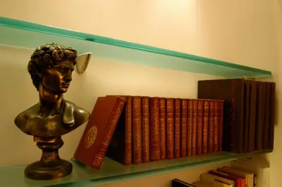 a book shelf with books and a bust on it at Hotel Garda in Rome