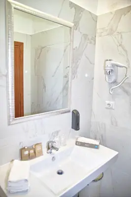 a white bathroom with a sink and a mirror at Hotel Hiberia in Rome