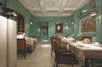 a dining room with tables and chairs and green walls at Stendhal Hotel in Rome