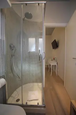 a glass shower in a bathroom with a bed at Quartopiano Guesthouse in Rome