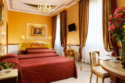 a hotel room with two beds and a desk at Hotel Principessa Isabella in Rome