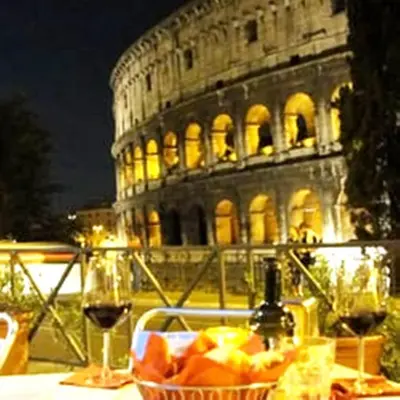 a basket of fruit and a glass of wine in front of the coliseum at Vesta Domus in Rome