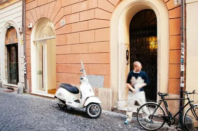 a man standing next to a scooter parked outside a building at All'Orologio in Rome