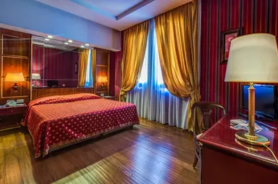 a bedroom with a bed and a desk with a lamp at Atlante Garden Hotel in Rome